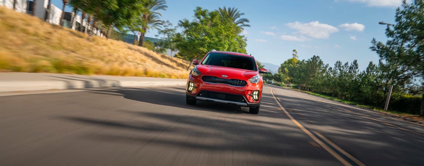 A red 2020 Kia Niro is shown from the front driving on a highway.