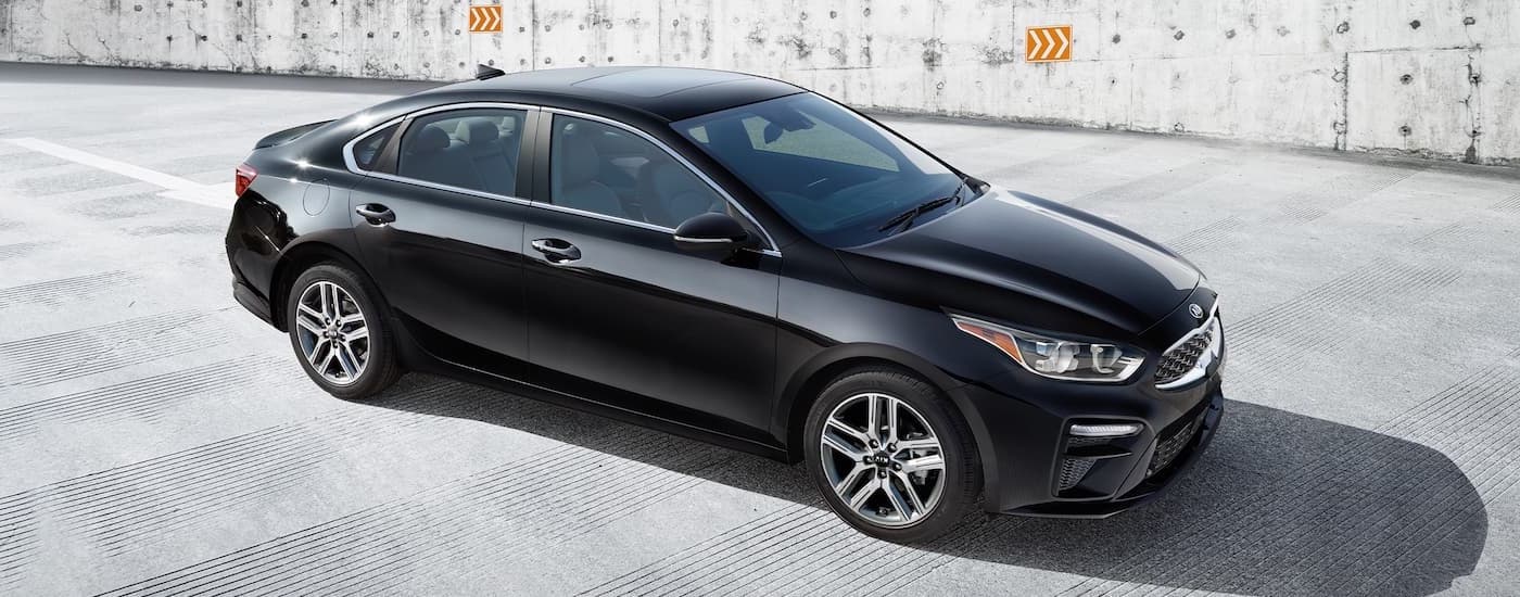 A black 2021 Kia Forte is shown from a high angle parked in a concrete parking garage.