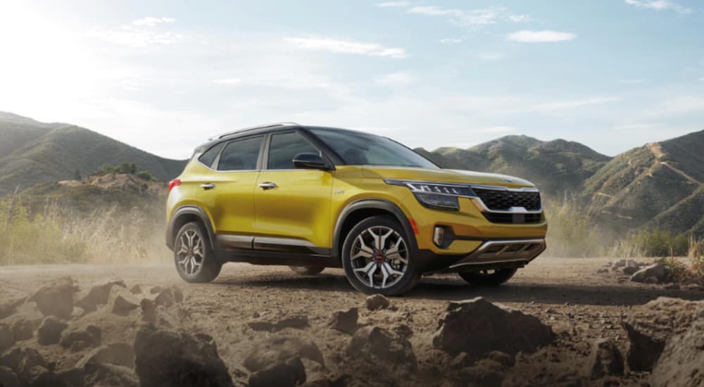 A yellow 2021 Kia Seltos is parked off-road in the desert.