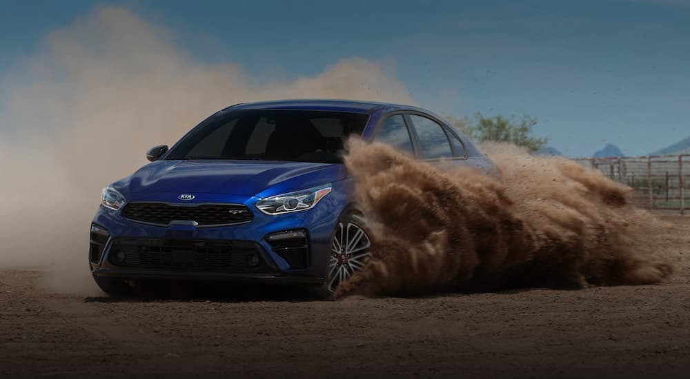 A blue 2020 Kia Forte is drifting in the dirt after leaving a Kia dealer near me.