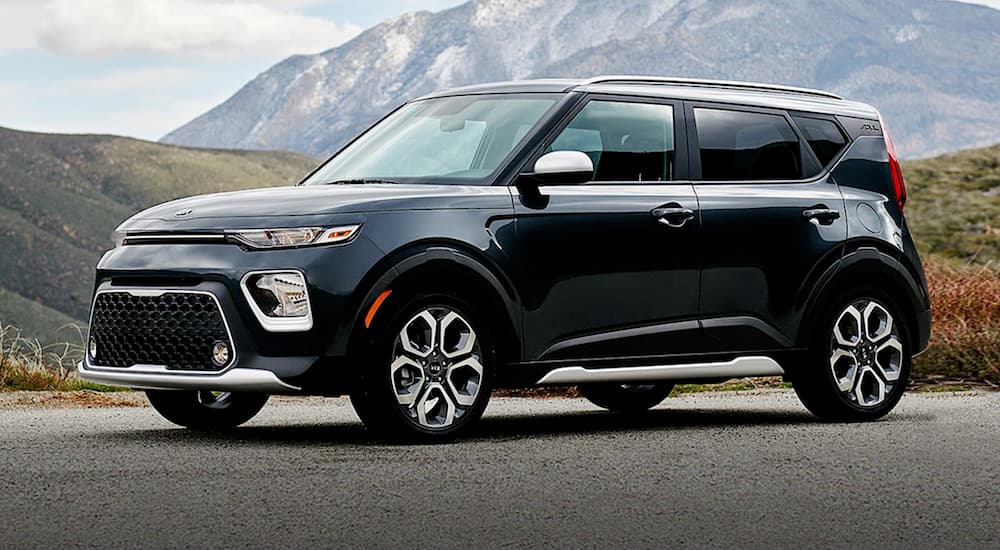 A black 2021 Kia Soul is parked in front of a mountain with snow.