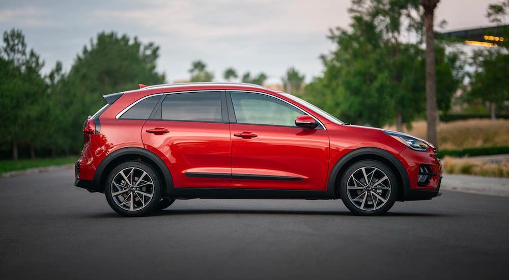 A red 2021 Kia Niro is shown from the side on a tree-lined road.