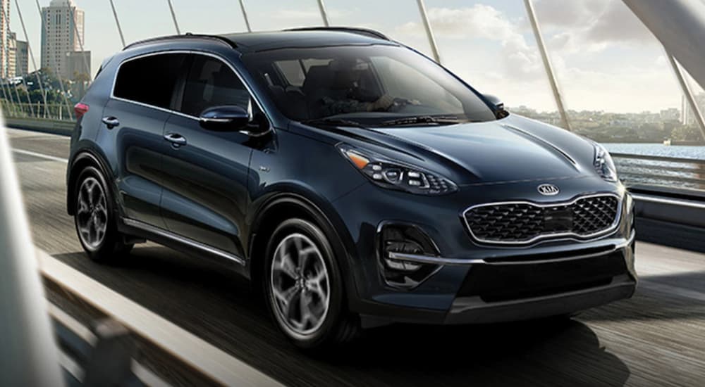 A blue 2022 Kia Sportage is shown driving over a bridge after leaving Kia dealers in Houston.