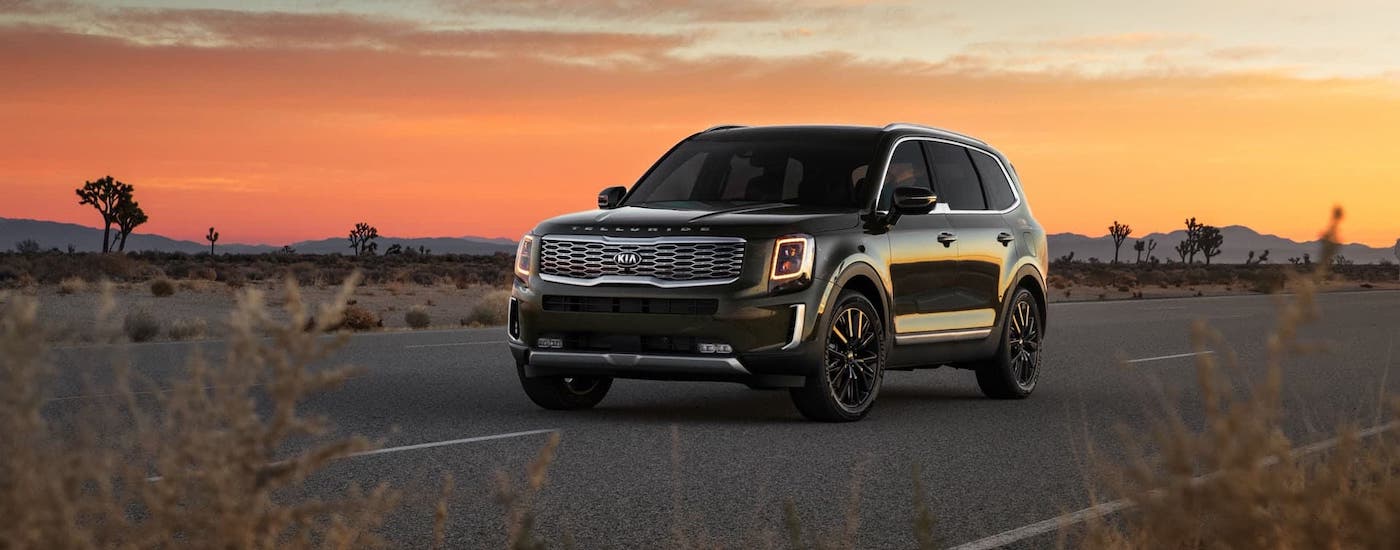 A black 2021 Kia Telluride is driving on a desert highway.