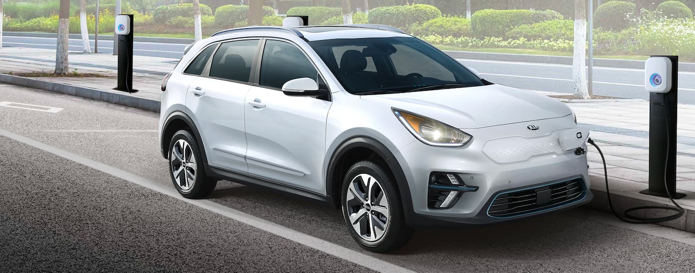 A white 2019 Kia Niro EV is shown charging at a public charging station.