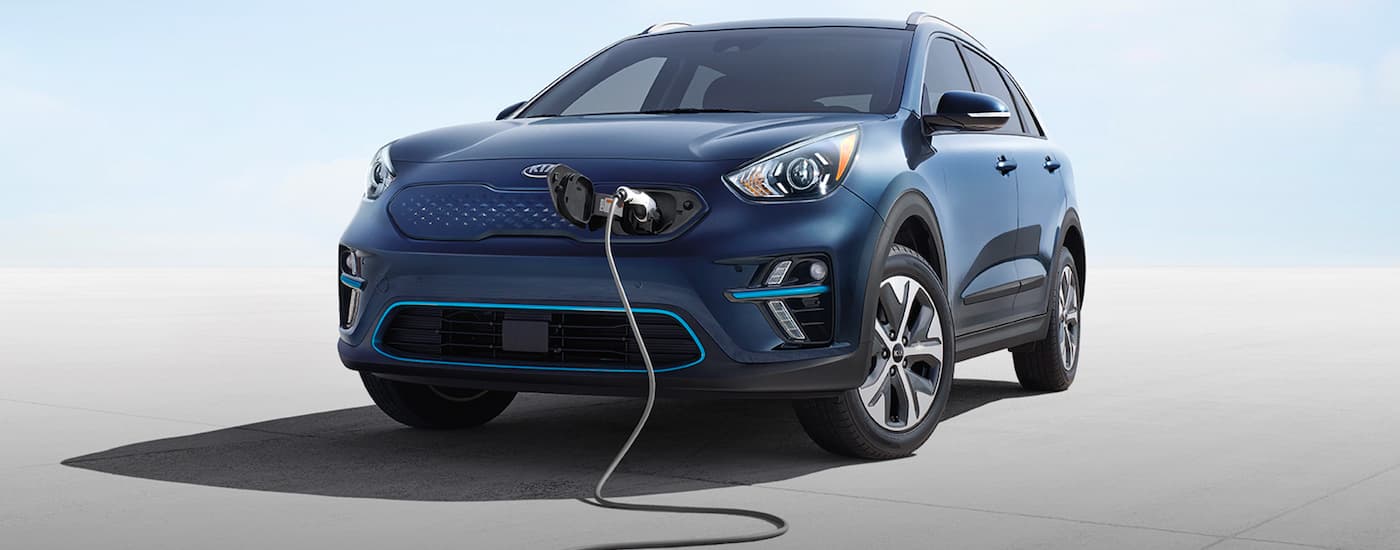 A blue 2020 Kia Niro EV is shown from the front while charging.